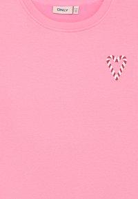 Sweatshirt cor-de-rosa feito de tecido macio, com um pequeno design de coração riscado em vermelho e branco na área do peito esquerdo.