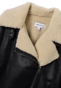 Giacca in similpelle nera con colletto in shearling color crema. Presenta chiusura con cerniera, tasche laterali e superficie strutturata. Etichetta visibile all'interno.