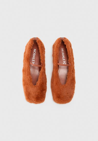 Oranžā pūkainā plakanā apavu pāris ar kvadrātveida purngalu un plānu siksniņu pāri augšai, attēlots no augšas uz balta fona.