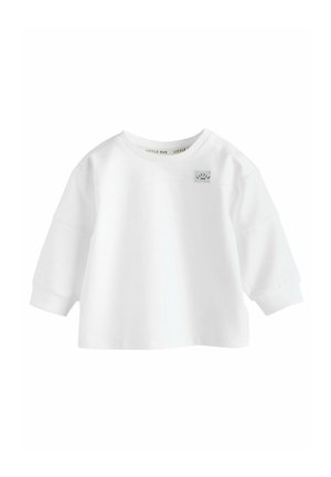 Valge pika varrukaga t-särk beebidele ümmarguse kaeluse ja õlgadel nööpide ning rinnal oleva väikese "Little Man" sildiga.