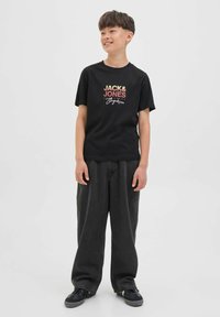 T-shirt noire avec impression graphique multicolore "JACK & JONES", associée à un jean noir ample et des baskets noires. Design décontracté, matériau en coton.