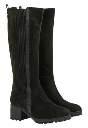 Par af høje sorte ruskindsstøvler med chunky lave hæle og ribstrikkede elastiske sidepaneler for nem påtagning.