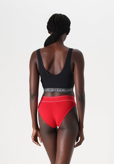 Μαύρο αθλητικό σουτιέν με ριμπ ύφανση και λογότυπο στη ζώνη, συνδυασμένο με κόκκινες ριμπ ψηλόμεσες εσώρουχες που διαθέτουν λευκές λεπτομέρειες.