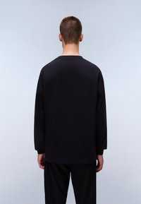 Black long-sleeve t-shirt with a crew neck, smooth texture, and relaxed fit. Featured on a person seen from the back.
