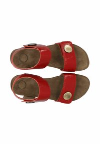 Punaiset patenttileather sandaalit, joissa on kaksi leveää remmiä, pyöreä metallinen nappikoriste ja pehmeä ruskea mokkanahkasisus. Avoin varvassuunnittelu.