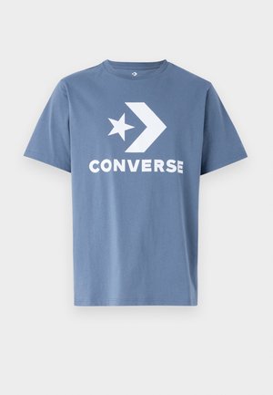 Blauw T-shirt met korte mouwen en een wit Converse-logo met stergrafiek in het midden van de borst, afgebeeld tegen een effen achtergrond.