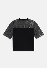 T-shirt noir à manches courtes avec un panneau supérieur à motif gris et une section inférieure noire unie, fabriqué en tissu doux avec une texture lisse.