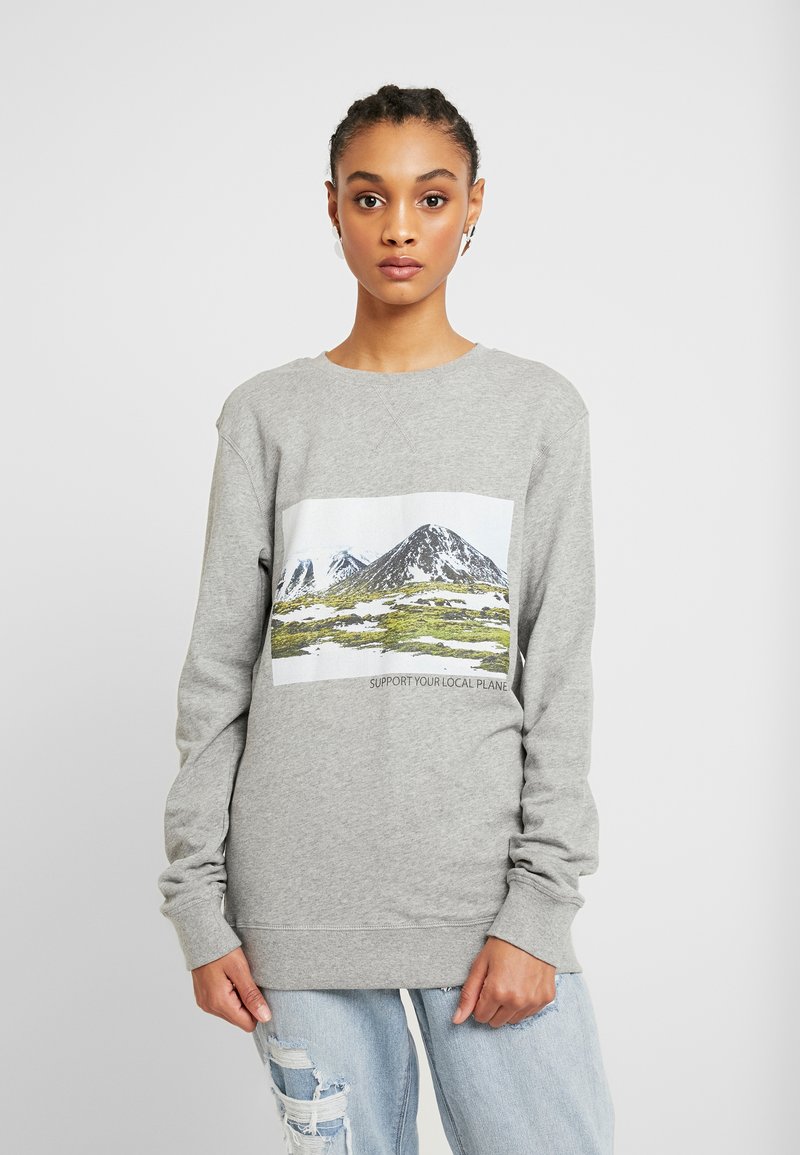 Sweatshirt cinza claro com uma ilustração frontal de montanhas e vegetação, apresentando o texto "APOIE O SEU PLANETA LOCAL." Mangas longas.