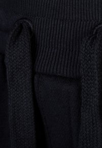 Navyblaue Jogginghosen mit einem gerippten Bund und gewebten Kordeln, hervorgehoben durch ein strukturiertes Strickmuster.
