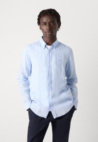 Lichtblauw button-up shirt van zachte stof, met een puntige kraag, lange mouwen en een klein geborduurd logo op de borst.