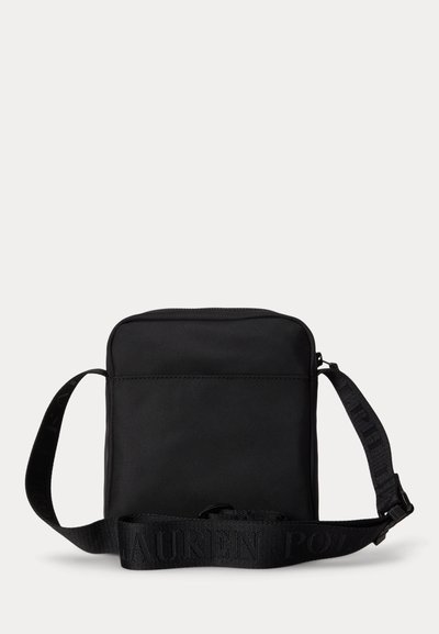 Small black square crossbody bag with adjustable shoulder strap featuring embossed brand name text.