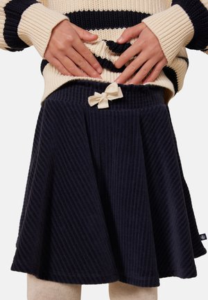 Marineblaue Cord-Rock mit ausgestelltem Design, ausgestattet mit einer cremefarbenen Schleifendetail an der Taille und vertikaler Rippstruktur.