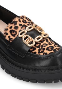 Mocassino in pelle nera con centro in pelliccia a stampa leopardata, dotato di un accento in catena dorata e una spessa suola in gomma nera con battistrada testurizzato.