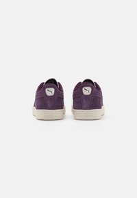 Baskets en daim violet avec des semelles en caoutchouc blanches. Présentent un badge logo et des accents texturés au niveau du talon. Design low-top avec une forme classique.
