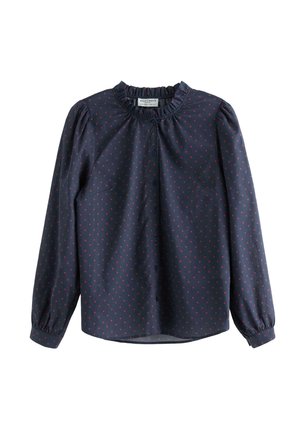 Tmavě modrá halenka s dlouhými rukávy, volánovým límcem a malým potiskem červených srdíček. Má zapínání na knoflíky a nařasené manžety pro lepší přizpůsobení.