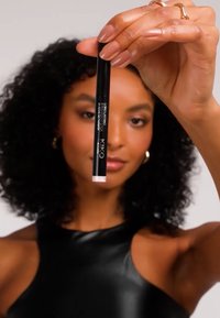 Lápiz de delineador negro con un acabado brillante, con una punta de color. La marca "KIKO" es visible en el costado. Mano sosteniéndolo sobre un fondo neutro.