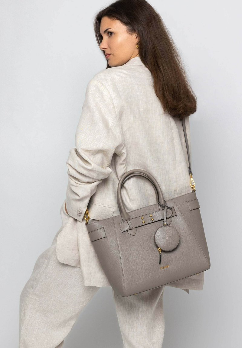 Sac fourre-tout en cuir gris avec un design structuré, équipé d'accents en métal doré, d'un pendentif circulaire détachable et de poignées doubles sur le dessus.