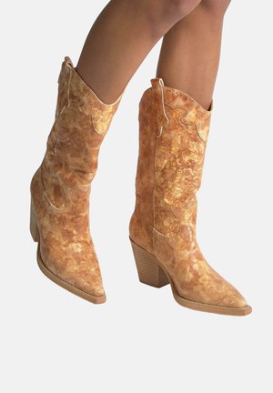 Botines de estilo occidental en tejido texturizado naranja, con punta afilada, tacón grueso y costuras decorativas a lo largo del borde superior.