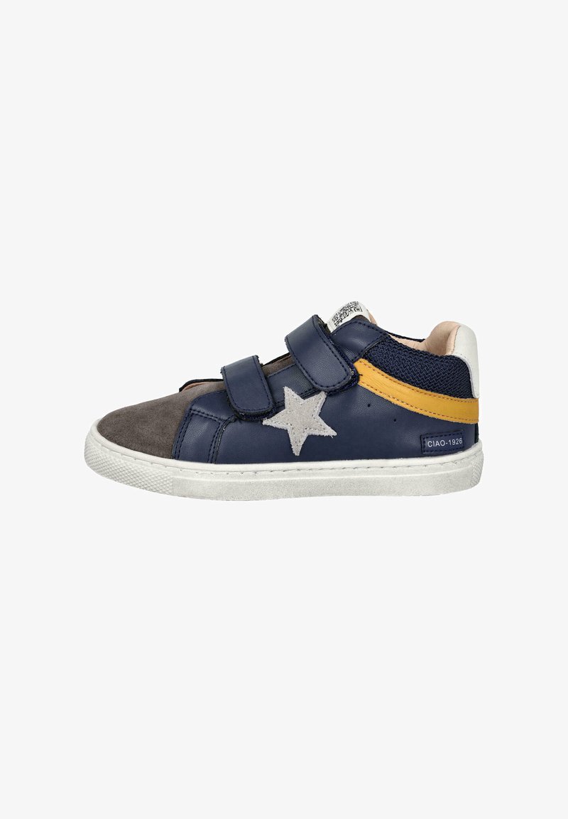 Zapatilla azul marino con puntera de ante gris, acento amarillo y detalle de estrella gris. Cuenta con dos tiras de velcro y una suela de goma blanca.