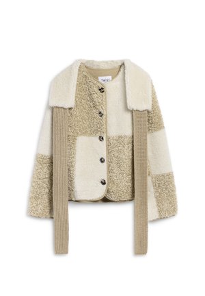 Giacca in patchwork beige e crema con texture morbida, colletto, cinque bottoni e pannelli laterali lavorati a maglia. Design corto e strutturato.