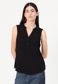 Blouse sans manches noire avec un col en V, patte de boutonnage et volants aux épaules. Fabriquée en tissu lisse et léger. Coupe décontractée.
