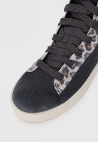 Schwarze Wildlederturnschuhe mit grauen Schnürsenkeln, die an der Seite einen Leopardenmuster-Akzent und eine strukturierte Zehenkappe aufweisen. Flache Gummisohle.
