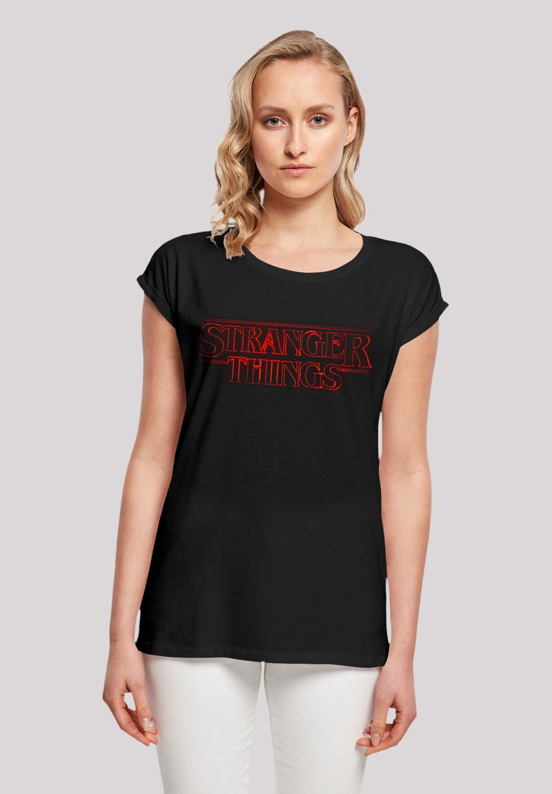 Black cotton t-shirt featuring "STRANGER THINGS" in bold, red lettering. Short sleeves and a relaxed fit with a round neckline.