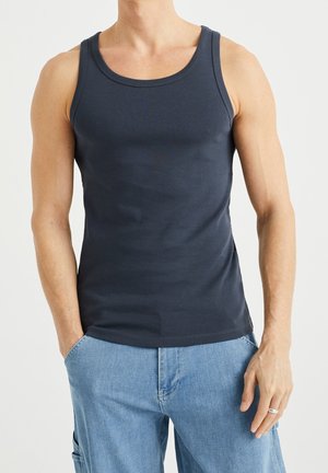 Marineblå bomulds-tanktop med rund halsudskæring og brede armhuller, der har en tætsiddende pasform og glat tekstur. Båret med lyseblå cargoshorts.