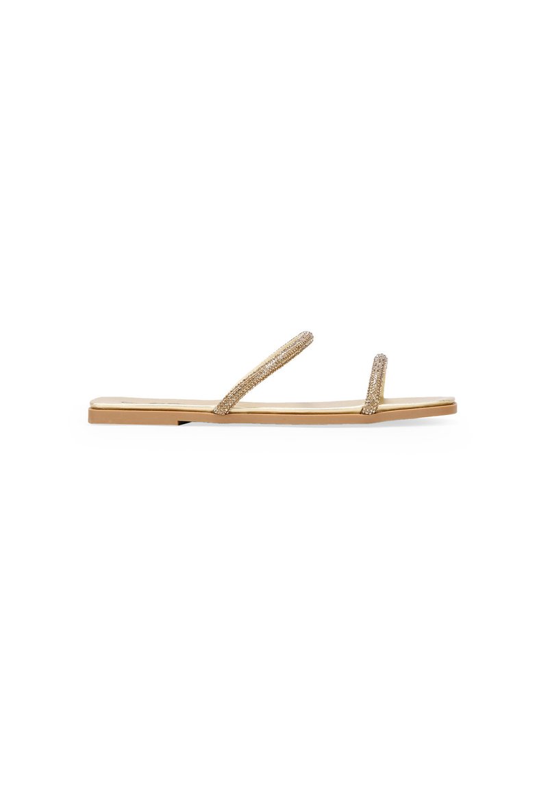 Sandalias planas con dos tiras delgadas y brillantes en color champán, una suela beige suave y un diseño simple y minimalista.