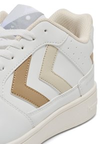 Białe sneakersy z teksturowanej skóry z beżowymi i kremowymi akcentami w zygzak. Posiadają lekką siateczkową język oraz wzmocnione oczka.