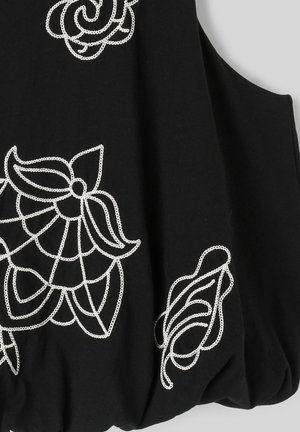 Vêtement noir sans manches avec broderie florale blanche présentant de grands pétales et des tiges courbes.
