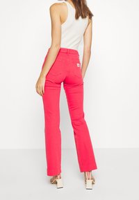 Rosa utsvängda jeans med hög midja, gjorda av denim. Har bakfickor och en liten logotypetikett på den bakre högra sidan.