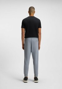 Svart kortärmad skjorta parat med ljusgrå byxor med elastisk midja och uppvikt fåll, bärs med svarta sneakers.