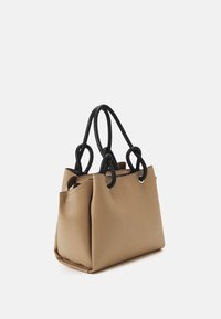 Skórzana torba w odcieniu brązowym z czarnymi uchwytami, z fakturowanym wykończeniem, okrągłymi wlotami dla uchwytów oraz przestronnym, miękkim kształtem.