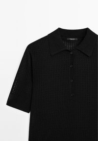 Zwart polo shirt met korte mouwen, voorzien van een gestructureerd, gebreid patroon, met een kraag en een placket met vier knopen.
