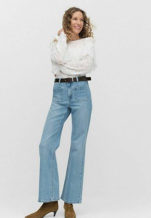 Ljusblå denimjeans med hög midja och vida ben, med bakfickor, kompletterade av en vit strukturerad topp och ett brunt bälte.
