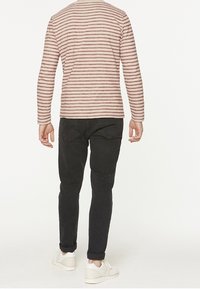 Raitapaitainen pitkähihainen paita vaaleanpunaisena ja viininpunaisena, yhdistettynä tummiin slim-fit-farkkuihin ja valkoisiin tennareihin. Takakuvassa näkyy paidan kaulus.