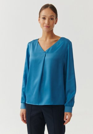 Satijnteal blouse met een V-hals, lange mouwen met elastische manchetten en een plooidetail aan de voorkant, wat zorgt voor een soepele textuur.