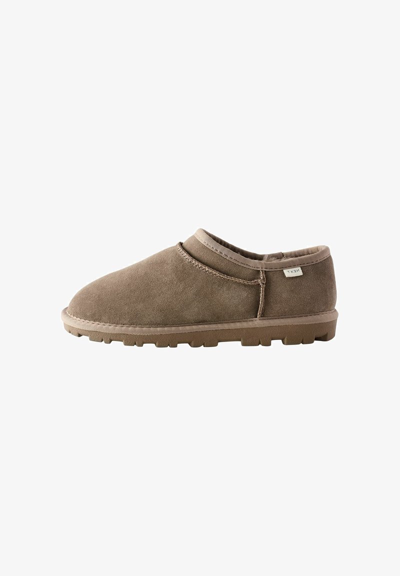 Scarpa slip-on in suede marrone con profilo basso, punta arrotondata e suola testurizzata, caratterizzata da cuciture sottili e un piccolo etichetta del marchio sul lato.