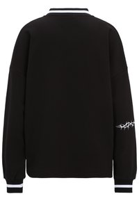 Sudadera negra con un cuello alto, con cuello y puños acanalados. Presenta franjas blancas en el cuello y un patrón de espinas en la manga derecha.