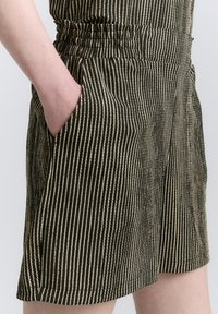 Pantaloni corti a righe neri e beige realizzati in tessuto leggero, con vita elasticizzata e tasche laterali per una maggiore comodità.