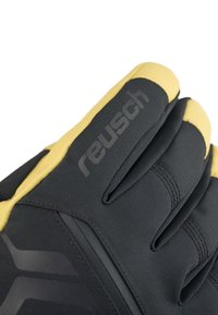 Sort og gule sportsvante med en tekstureret overflade, der har et strømlinet design og præget branding på bagsiden.