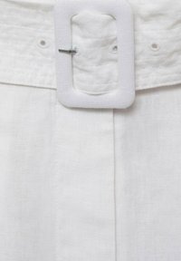 Ceinture en lin blanc dotée d'un tissu texturé, d'une boucle rectangulaire blanche mate et d'un extrémité argentée pour la fixation.