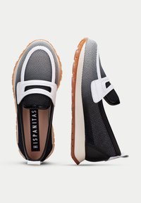 Scarpe slip-on in bianco e nero con materiale in rete, suola in gomma e dettagli testurizzati. Presentano una punta rotonda e un tallone flessibile.