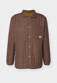 Bruine gevoerde jas met een kraag, twee borstzakken, drukknoopsluiting en een contrasterende gele voering. Voorzien van horizontale stiksels.