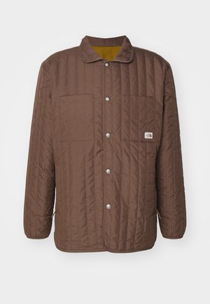 Geacă maro matlasată cu guler, două buzunare pe piept, nasturi cu capse și o căptușeală galbenă în contrast. Prezintă cusături orizontale.