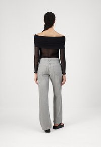 Black off-shoulder top with gathered detailing, paired with high-waisted gray wide-leg jeans, featuring back pockets and a relaxed fit.
