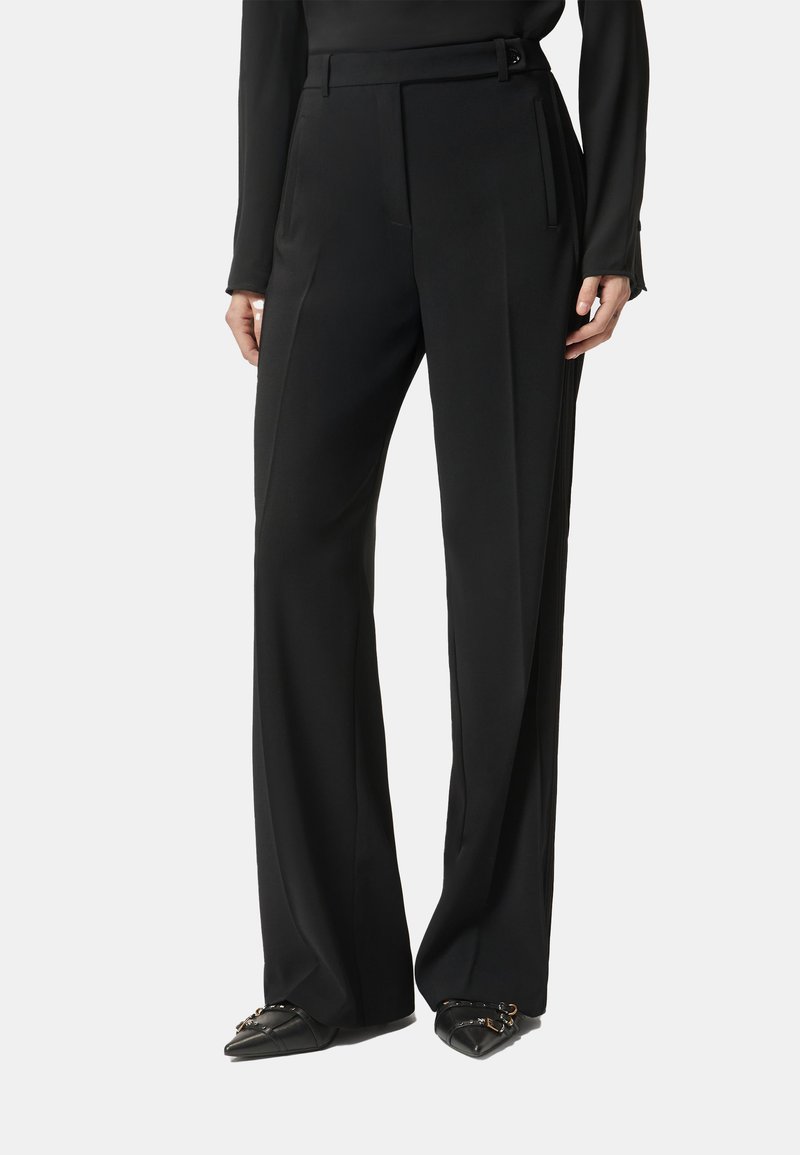 Pantaloni neri su misura con vita alta, gambe larghe e dettaglio cinturino. Tessuto liscio con pieghe a contrasto e tasche laterali.