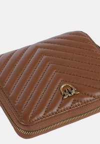 Portafoglio marrone in pelle con cerniera, caratterizzato da un motivo trapuntato a chevron, con logo in tono oro e dettagli della cerniera in oro. Forma compatta e rettangolare.