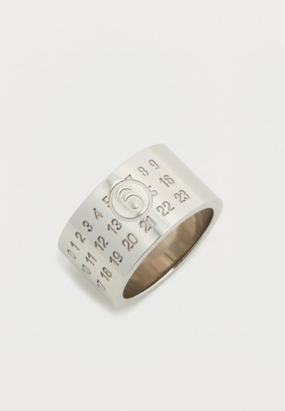 Ασημένιο δαχτυλίδι με φαρδιά μπάντα που διαθέτει χαραγμένους αριθμούς και ένα κεντρικό '6' μέσα σε κυκλικό διακοσμητικό στοιχείο, με λεία υφή και γυαλιστερό φινίρισμα.